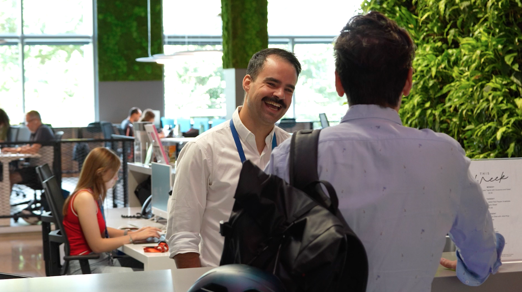 Receptionist looks excited towards a visitor in an urban workplace